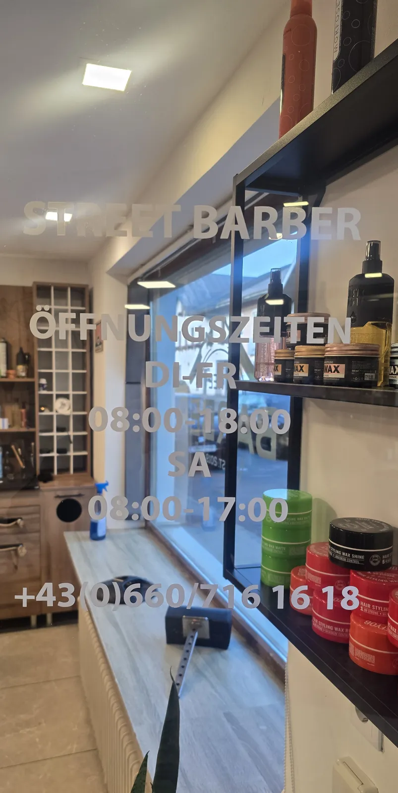Schaufenster mit Aufschrift Öffnungszeiten Di–Fr 08:00–18:00, Sa 08:00–17:00 und Telefonnummer, daneben Styling-Produkte