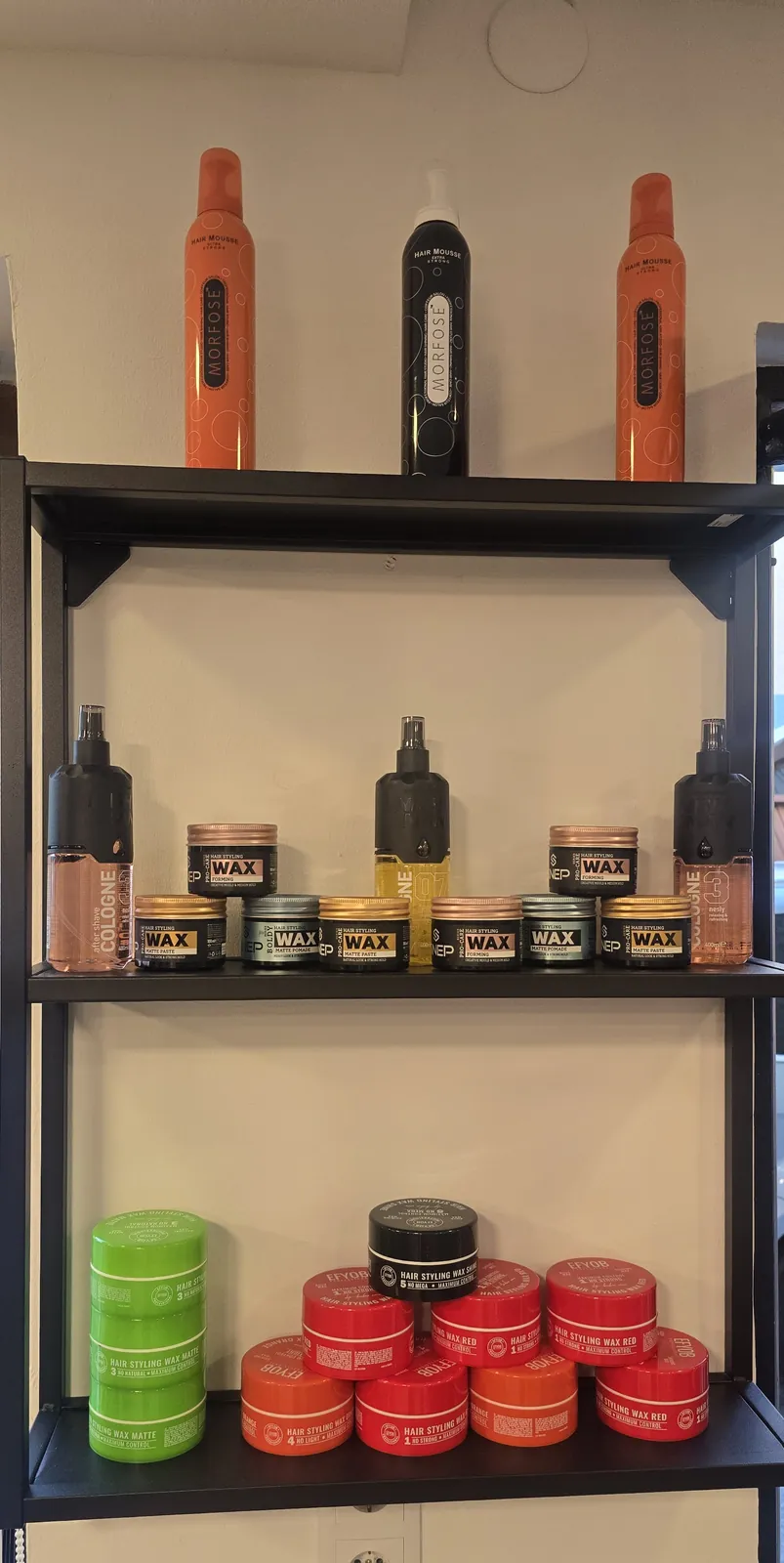 Wandregal mit Haarwachs-Dosen, Cologne-Flaschen und Haarspray